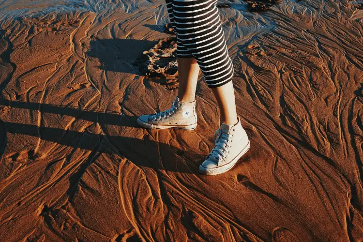 a woman walking in converse shoes