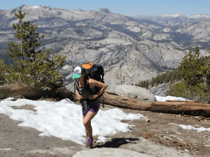 a female backpacker with a backpack at the snowy mountains