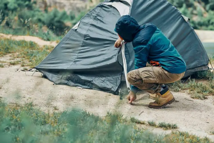 a man putting tent pegs