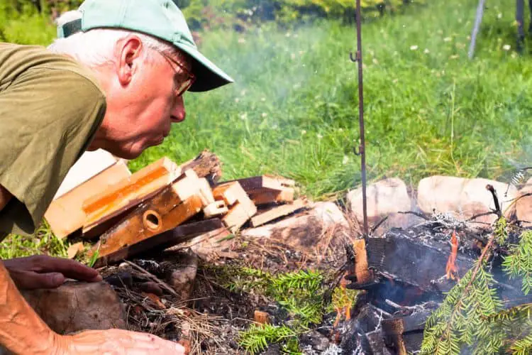 an old man blowing on a fire