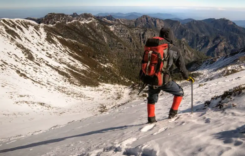 man hiking on a snowy mountain hill