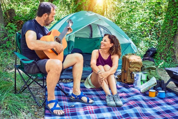 a couple camping sitting on a tent carpet