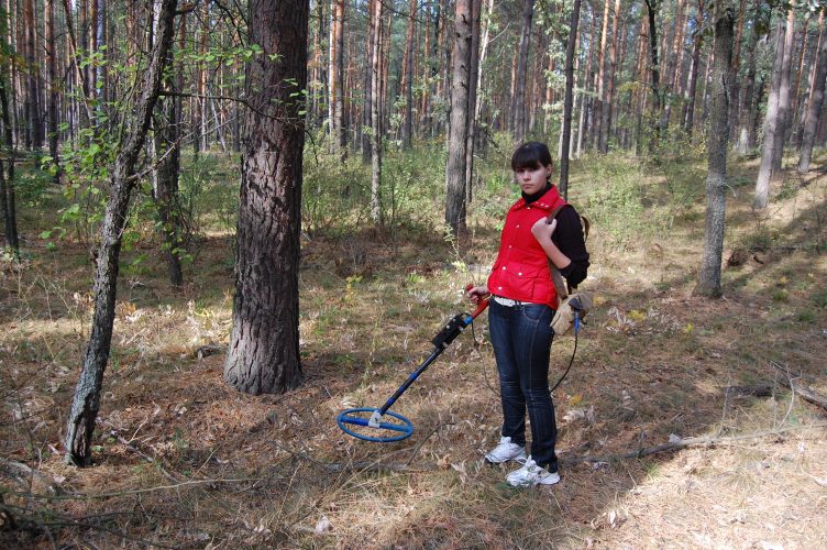 girl metal detecting in the woods