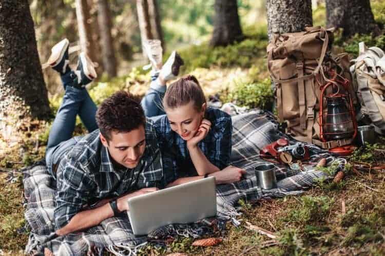 couple with a laptop in the woods