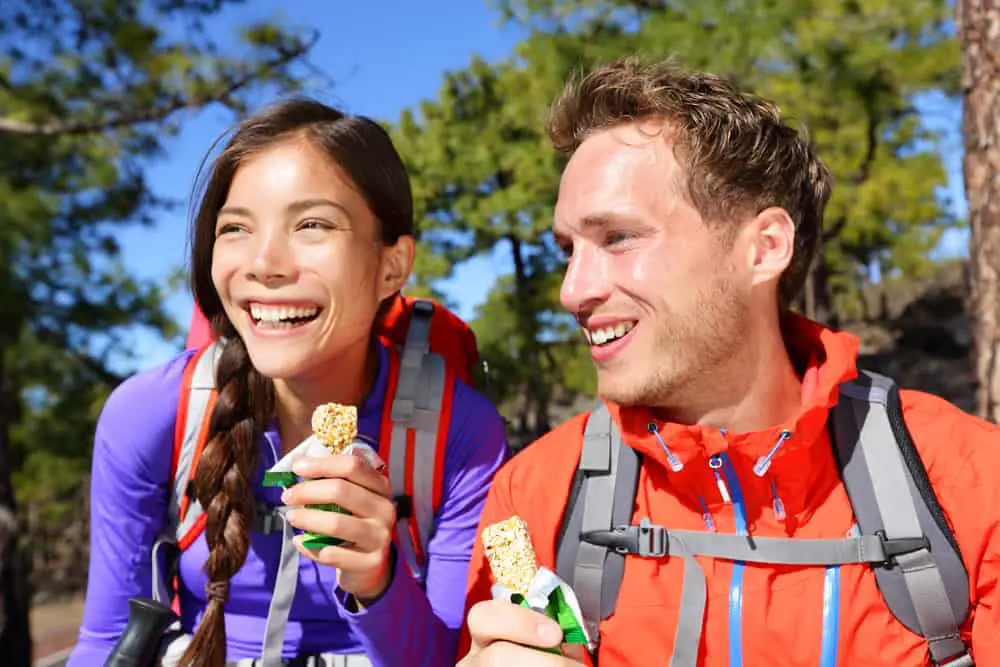 a couple eating energy bars while hiking