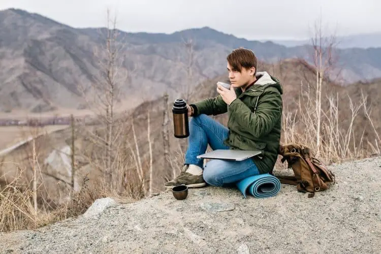 man drinking water while hiking