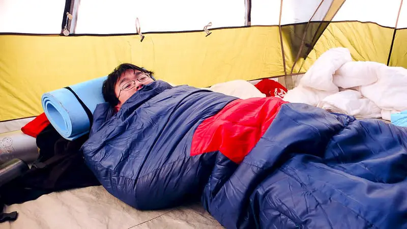 a man in a sleeping bag in a tent